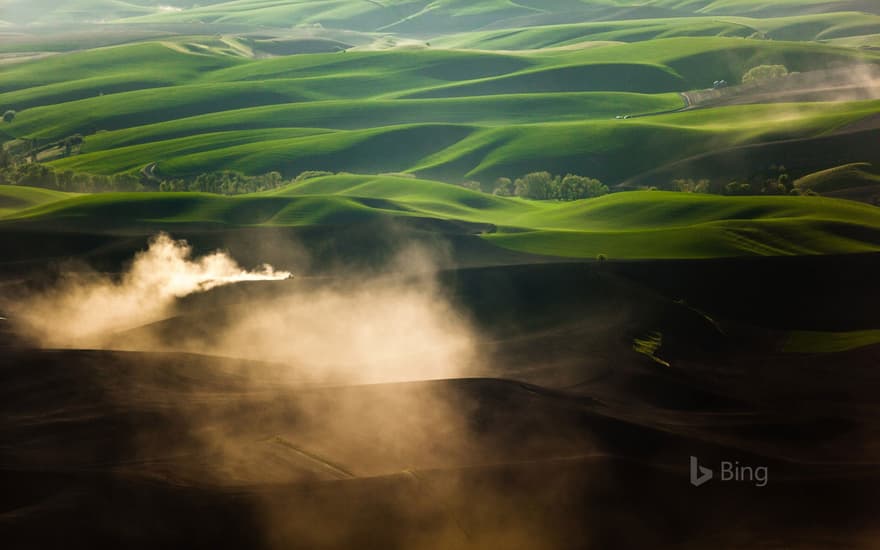 A tractor kicks up dust while tilling fields on the Palouse near Pullman, Washington